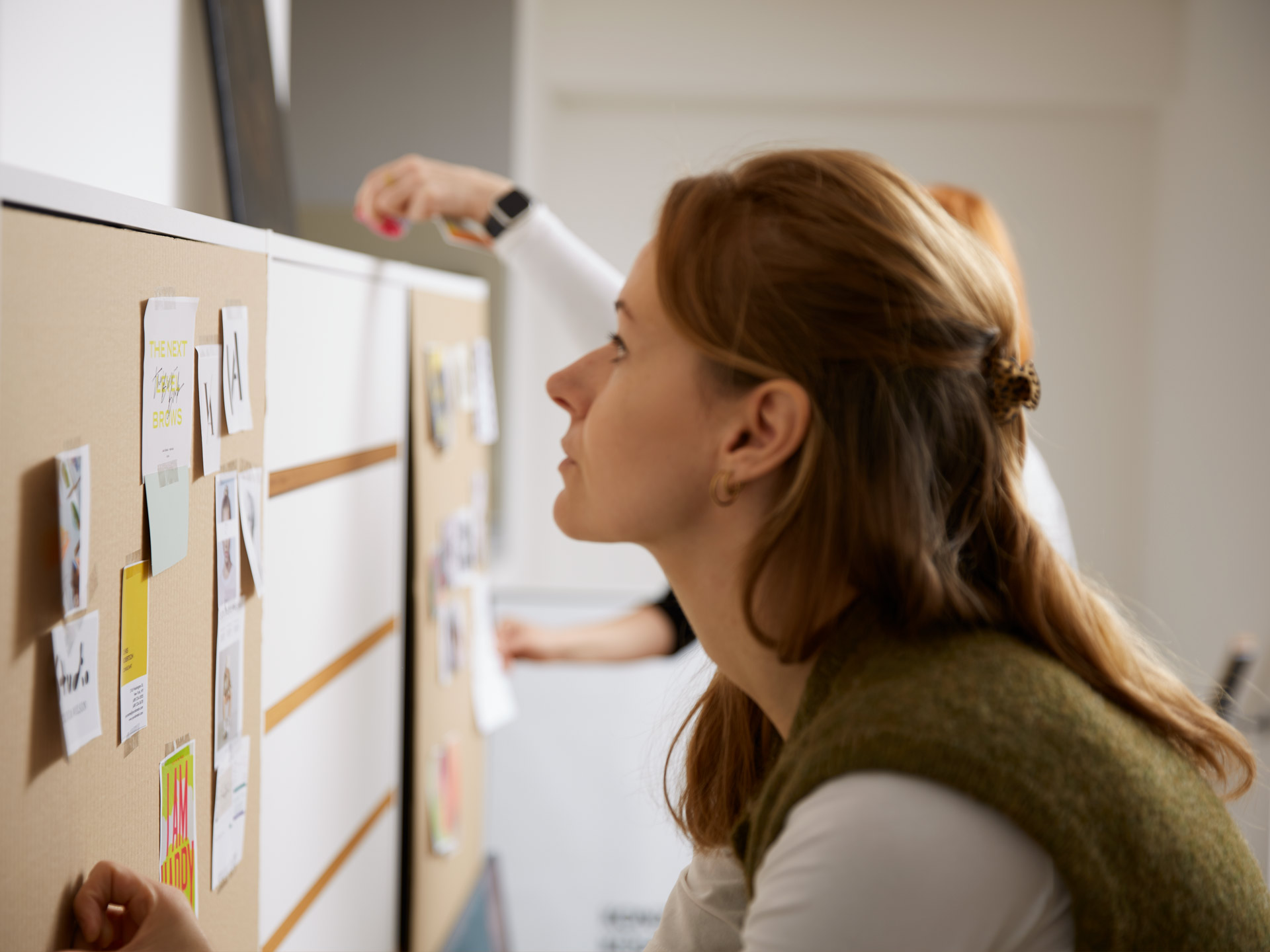 7-workshop-teilnehmerin-vor-pinwand Teilnehmerin steht vor ihrer Workshop-Pinwand und betrachtet die aufgehängten Materialien